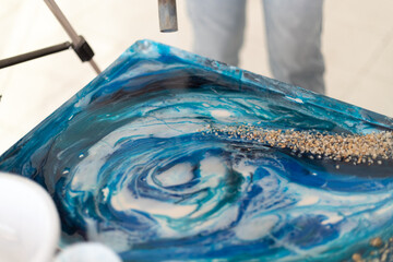 Epoxy resin different blue color in cup for casting stabilizing wood, abstract art. Process of...