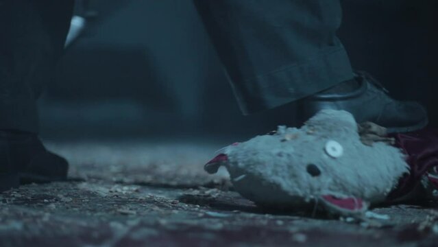 Close-up shot of a man crushing down a teddy bear. Man stepping or walking on a teddy bear in dramatic light.
