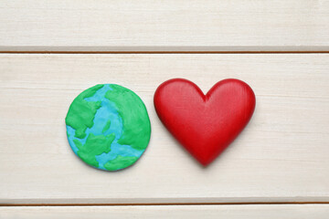 Happy Earth Day. Plasticine planet and decorative heart on white wooden table, flat lay