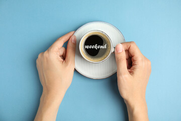 Happy Weekend. Woman with cup of hot aromatic espresso on light blue background, top view