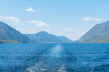Straight ship trace and landscape with mountains and lake. Altai Republic, Lake Teletskoye.