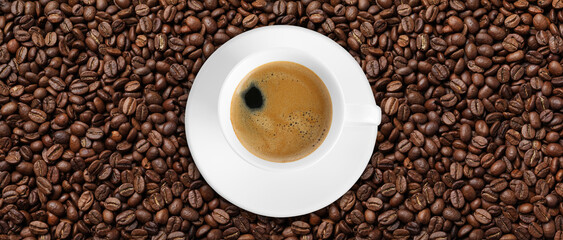 Cup of tasty aromatic coffee on roasted beans, top view. Banner design