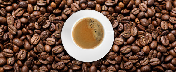 Cup of tasty aromatic coffee on roasted beans, top view. Banner design