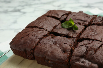 Cooling rack with delicious freshly baked brownies on white table, closeup