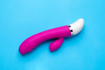 Pink vaginal vibrator on light blue background, top view. Sex toy