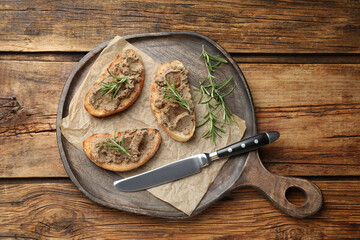 Slices of bread with delicious pate and rosemary on wooden table, top view