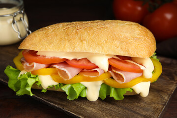 Delicious sandwich with vegetables, ham and mayonnaise on wooden table, closeup