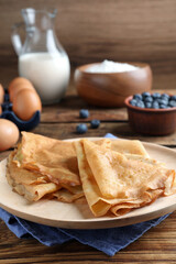 Delicious crepes served on wooden table, closeup. Space for text