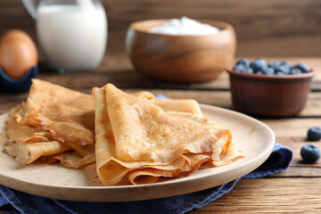 Delicious crepes served on wooden table, closeup. Space for text