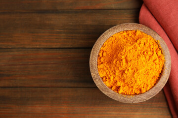 Aromatic saffron powder in bowl on wooden table, flat lay. Space for text