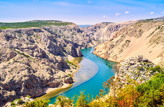 Canyon at the river Zrmanja in Croatia with steep cut into the Dalmatian limestone massif and an excursion boat in the background