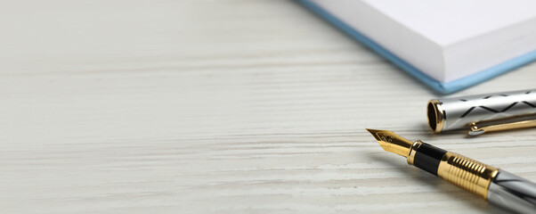 Naklejka premium Beautiful fountain pen with ornate nib on white wooden table, closeup view with space for text. Banner design