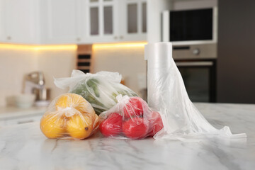 Fototapeta na wymiar Plastic bags with different fresh products on white marble table in kitchen
