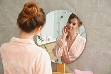 Beautiful woman wearing pink bathrobe in front of mirror at home - obrazy, fototapety, plakaty