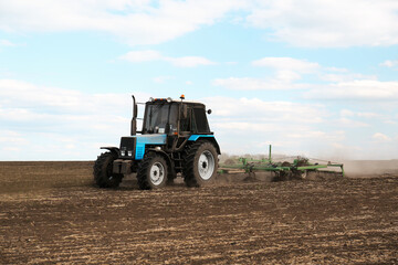 Fototapeta na wymiar Tractor with planter cultivating field on sunny day. Agricultural industry