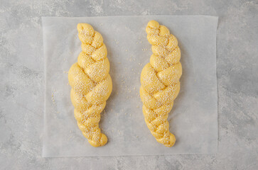 Raw loaf of challah Jewish bread on a light gray background. Top view, copy space.