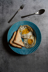 Breakfast food item bread slices and egg in a blue bowl on a background. Top view, selective focus.