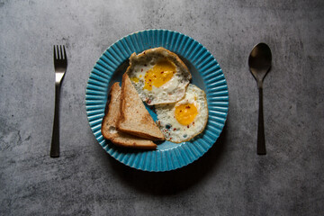 Breakfast food item bread slices and egg in a blue bowl on a background. Top view, selective focus.