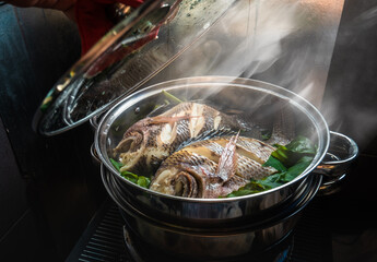 Two fish in a steamer set on the stove. The lid was opened and smoke floated.