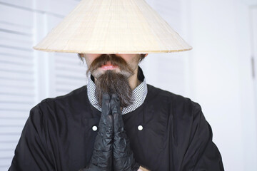 A hilarious parody of an Asian man in a Vietnamese hat with a beard. Portrait. Asian cafe chef.