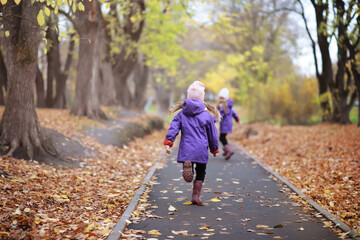 Young family on a walk in the autumn park on a sunny day. Happiness to be together.