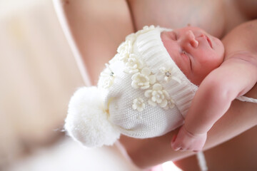 A newborn baby lies in her mother's arms. A beautiful baby of European appearance is sleeping.