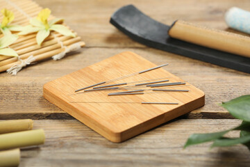 Board with acupuncture needles on wooden table