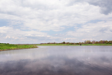 River near village under sky with clouds. Picturesque landscape