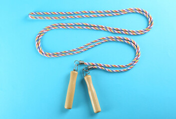 Skipping rope on light blue background, top view. Sports equipment