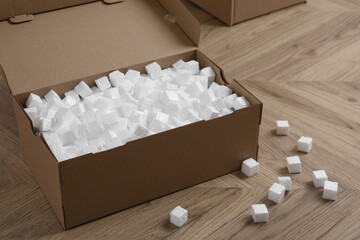 Cardboard box and styrofoam cubes on wooden floor