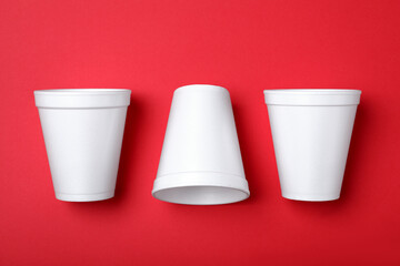 White styrofoam cups on red background, flat lay