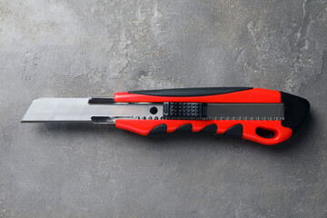 Utility knife on grey table, top view. Construction tool
