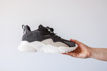 Stylish men's sneakers in hand on a white background