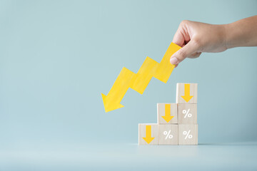 Yellow paper cut arrow going down negative trend on wooden blocks with percentages. Concept of...
