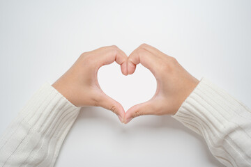 Hands doing heart shape sign on light background. Woman hand gesture showing love sign.