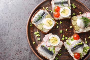 Rye bread toasts with butter, sprat fillet, eggs, various vegetables close-up in a plate on the table. horizontal top view from above
