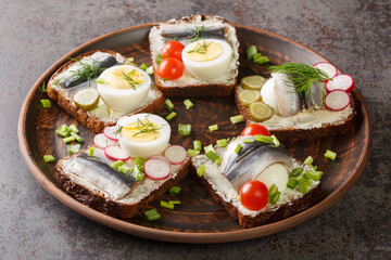 Estonian traditional delicacy kiluvoileib sandwich with fish, egg and butter close-up in a plate on the table. horizontal