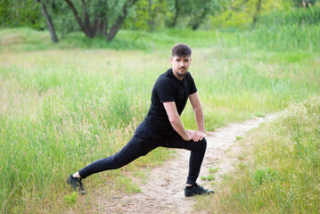 A male athlete stretches his legs in nature