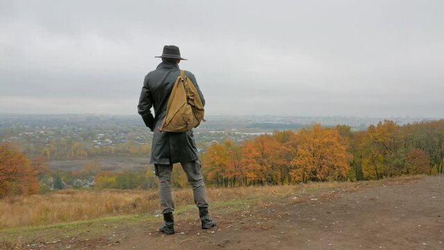 silhouette of a man stands on a hill and looks at the city