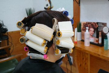 Back view of woman doing perm in beauty salon