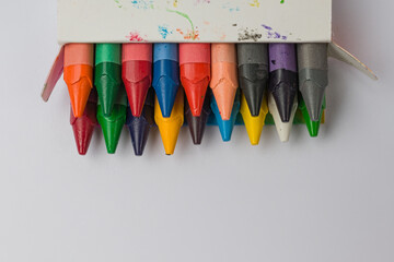 open box with wax colored crayons on white background with copy space