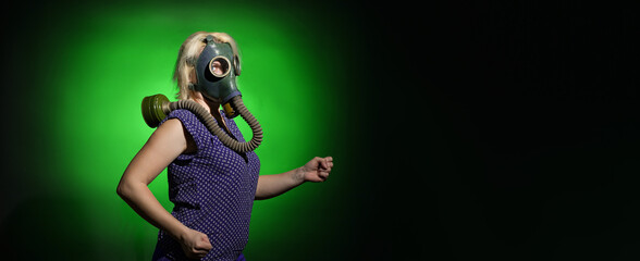 Fototapeta na wymiar a woman in a gas mask walks on a dark background with copy space