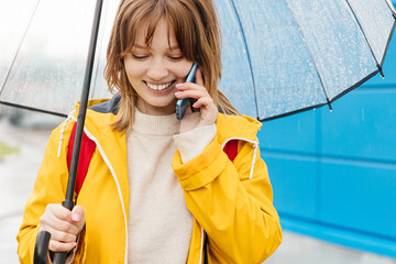 girl under an umbrella talking on a mobile phone
