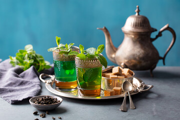 Moroccan mint tea in traditional glasses on silver tray. Grey and blue background. Copy space. - 506362432