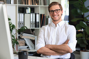 Portrait of young man sitting at his desk in the office.