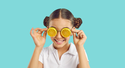 Headshot portrait of funny teen girl in cool orange sunglasses isolated on blue studio background....