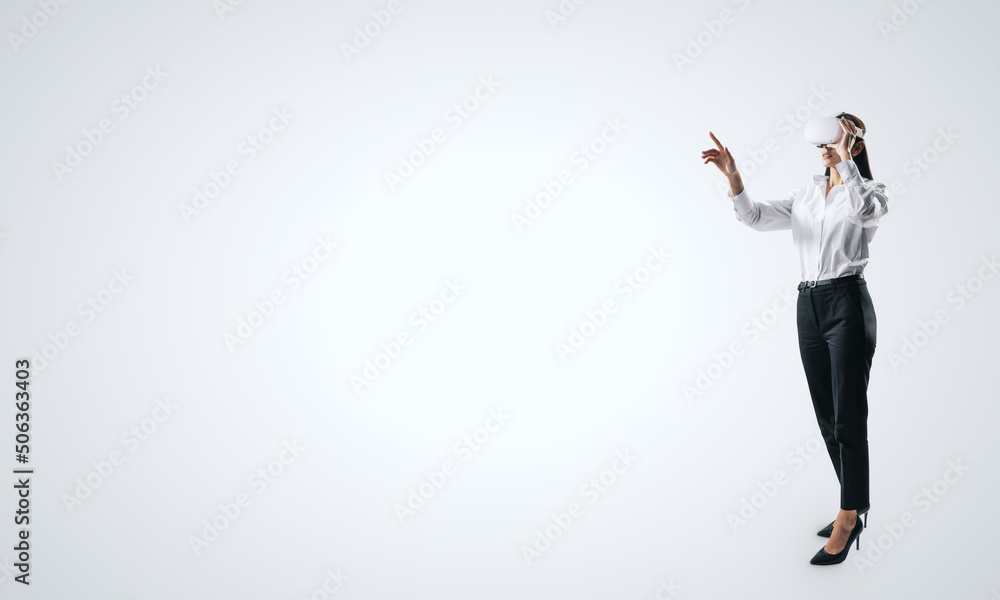 Poster woman full length standing and working in virtual reality environment in vr glasses, presses by her 