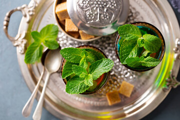 Moroccan mint tea in traditional glasses with sugar on silver tray. Close up. Top view.