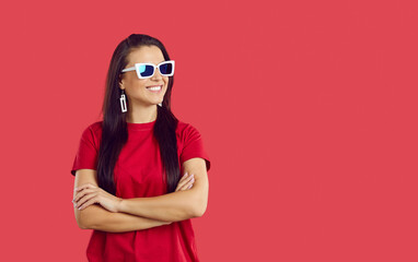 Smiling young woman in sunglasses isolated on red studio background look at empty copy space aside. Happy stylish female in glasses consider good sale deal or promotion offer. Advertising.