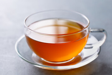 Tea in glass cup. Grey background. Close up.